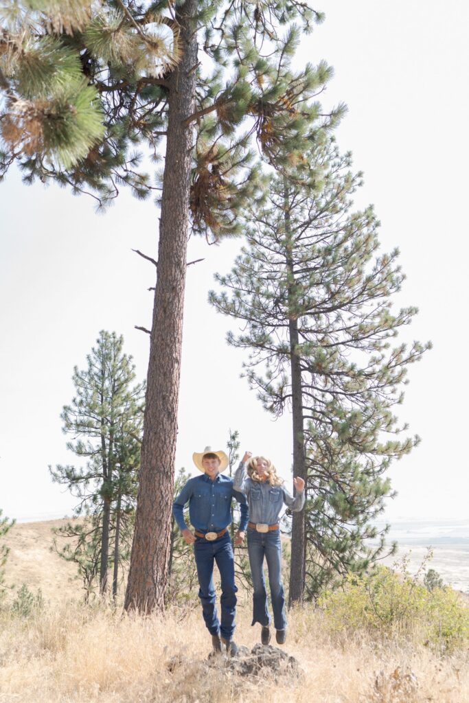 Young boy and girl jump on top of a hill in Oregon.