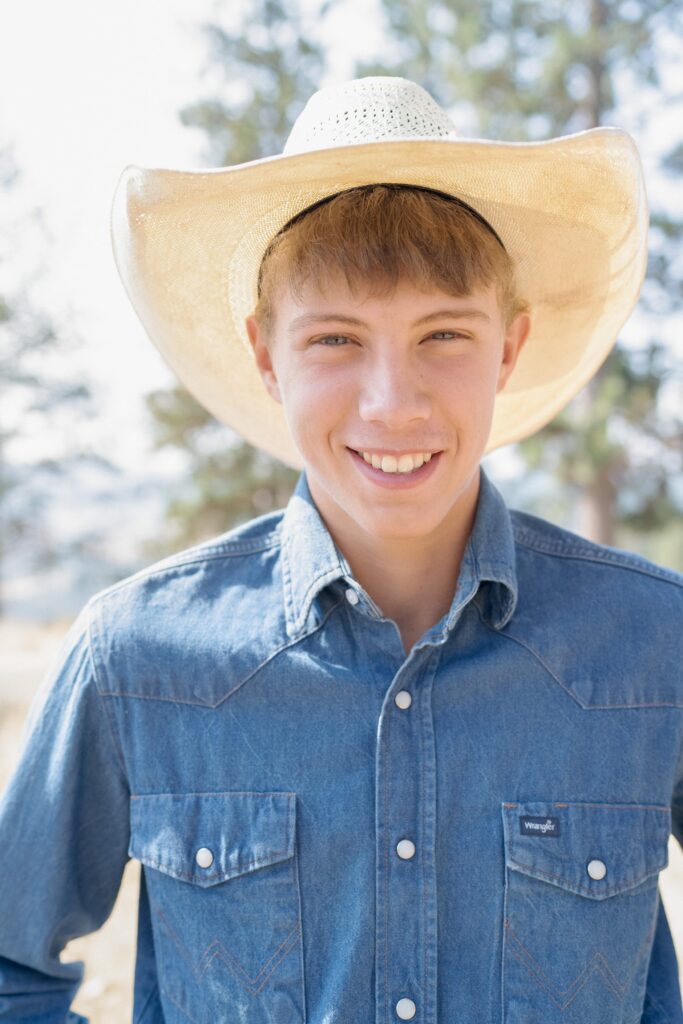 Charming young man in a blue denim jacket and white cowboy hat.