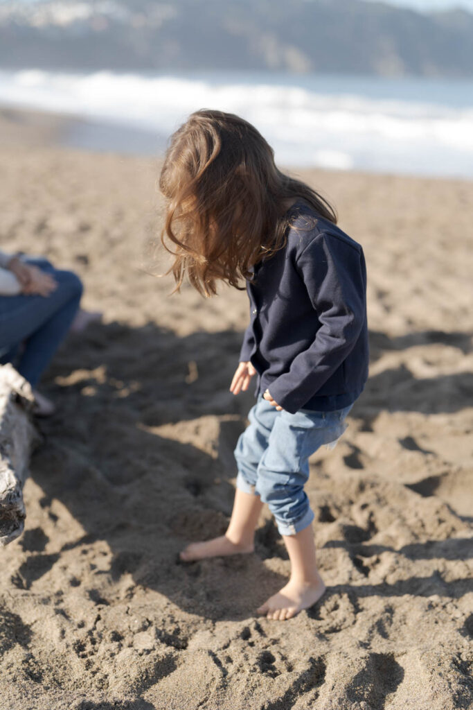 Young girl with long hair playing with the beach sand.