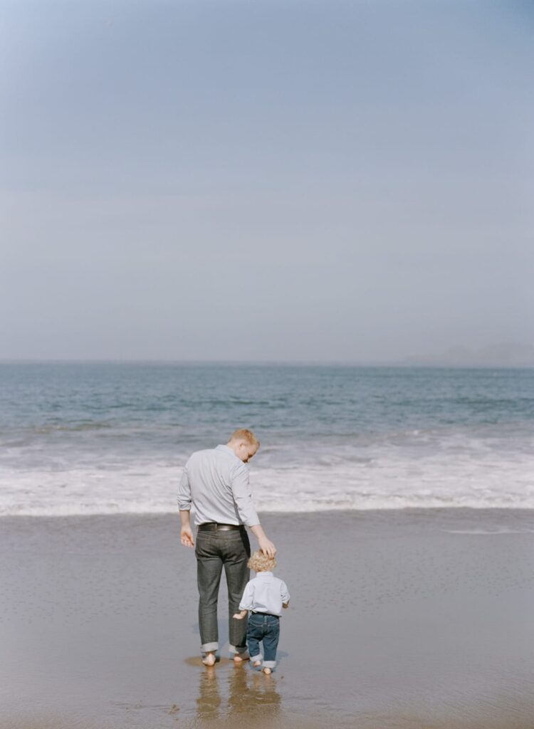 A father guides his young son into the nearshore waters of Baker Beach.