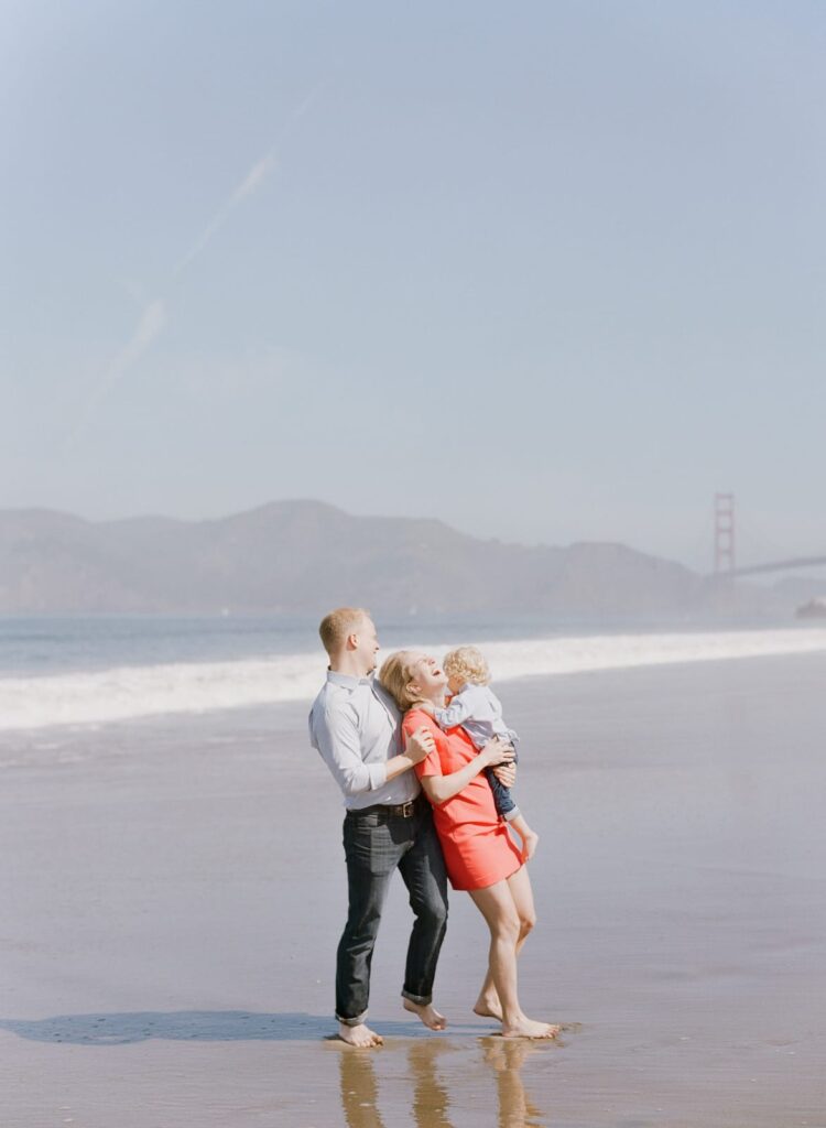 A married couple and their child walking in nearshore waters.
