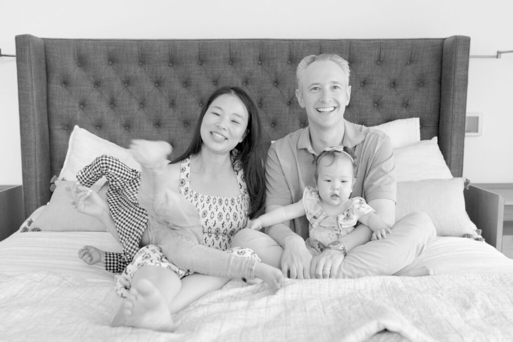 A beautiful family of four sit on a large bed.