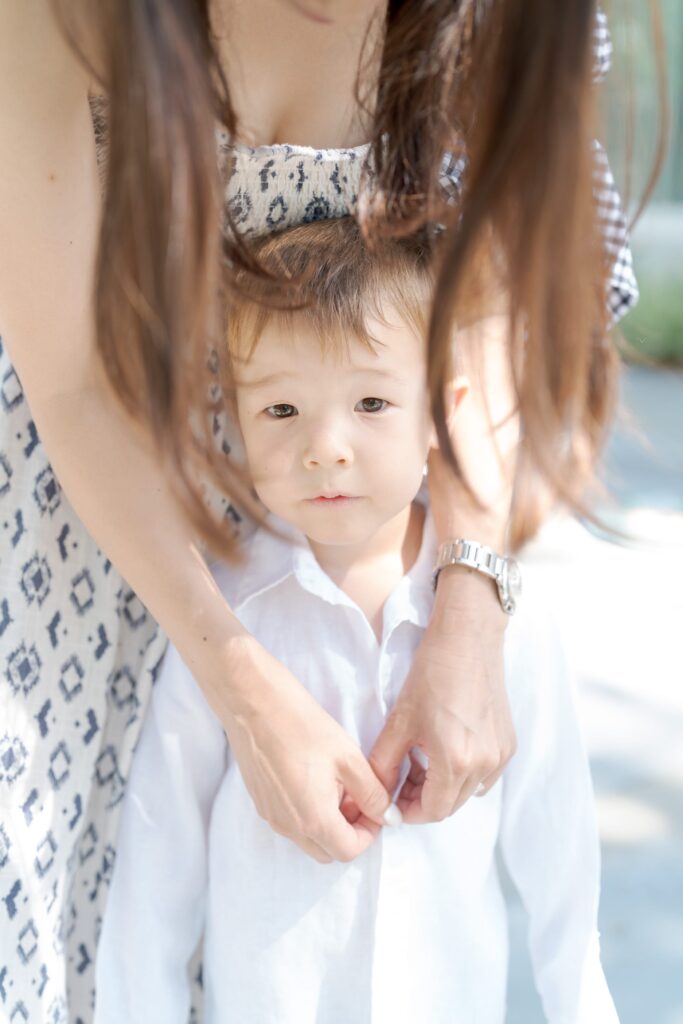 Mom buttoning the white shirt for his son.