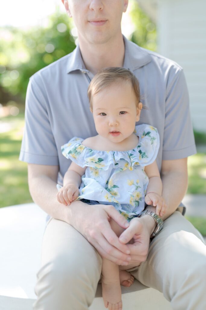 Baby daughter sits on her father's lap.