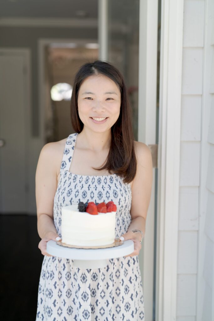 Happy mom holds a cute white cake with strawberries on top.