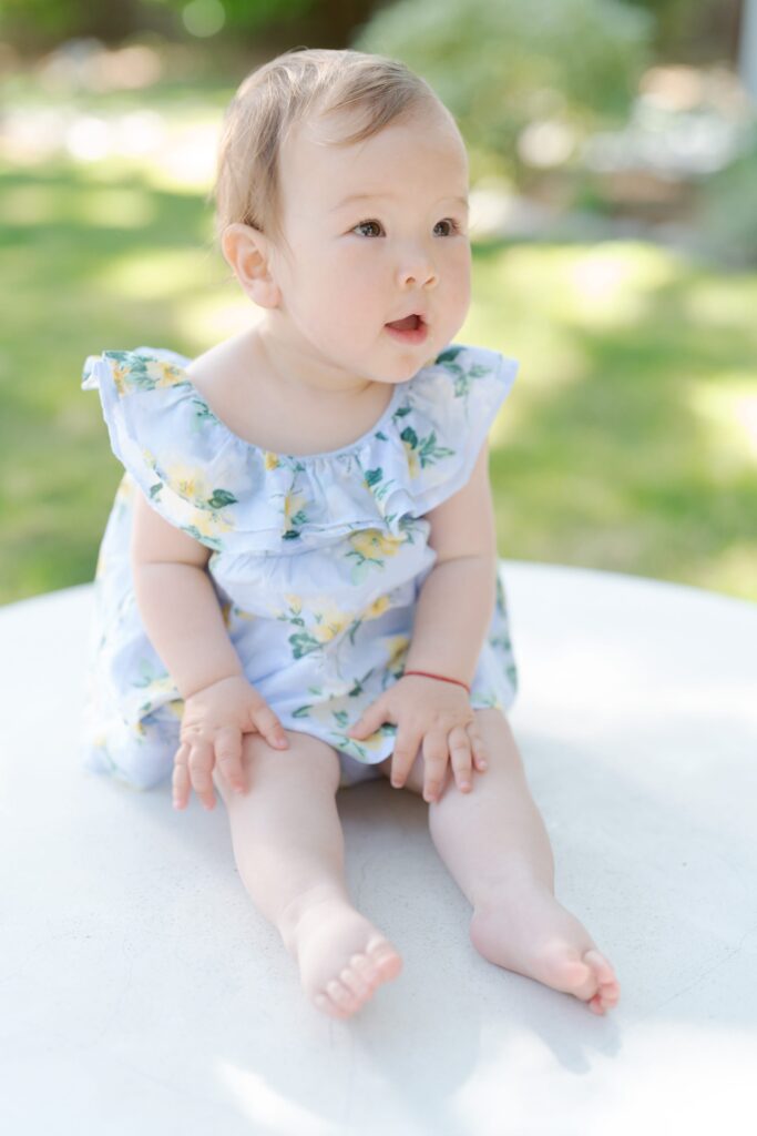 Cute baby girl with blonde hair sits adorably.