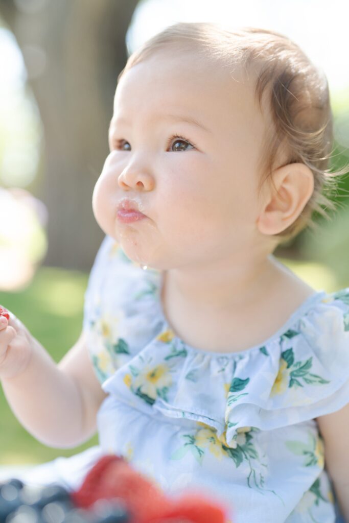 Baby daughter eats cake and strawberries and looks up.