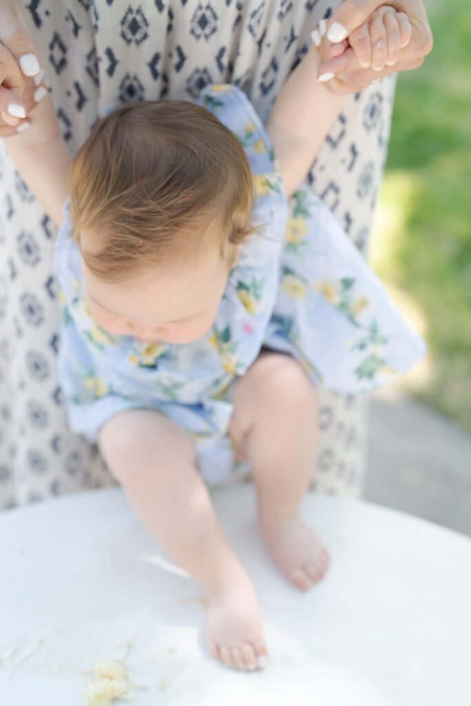 Mother holds her baby daughter by her arms.