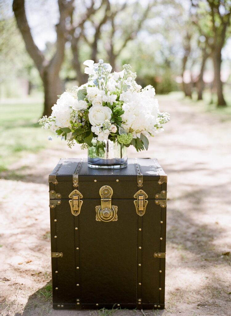A color image of wedding ceremony decor. Flowers in a vase on an old trunk.