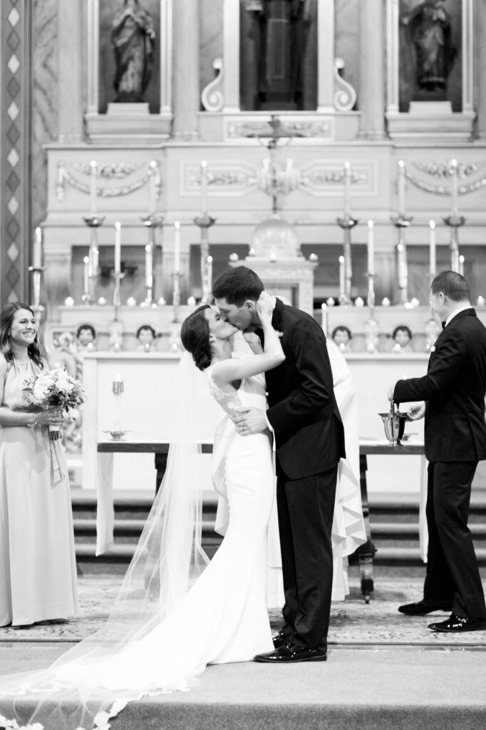 A black and white image of a couple kissing after exchanging vows at the Mission Santa Clara de Asís