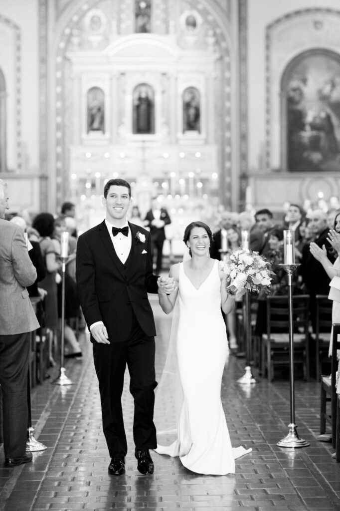 Black and white image of a couple at Mission Santa Clara de Asís about to walk up the aisle as husband and wife.
