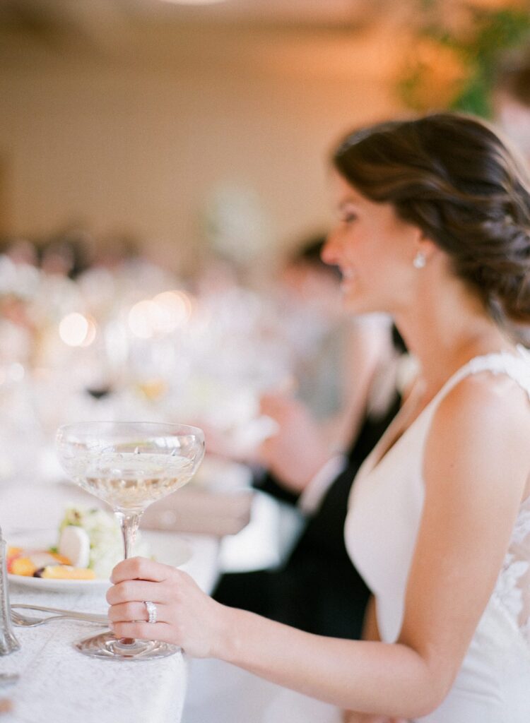 a picture of a bride sitting at the dinner table with an amazing crystal champagne glass.