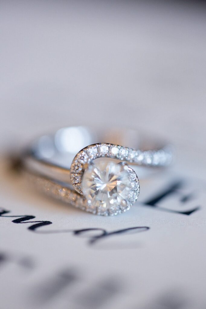 A color photograph of a diamond ring with smaller diamonds framing the center diamond. 