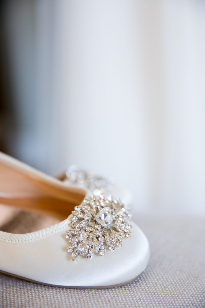 Color photograph of white satin flats with dimonds on the toes. 
