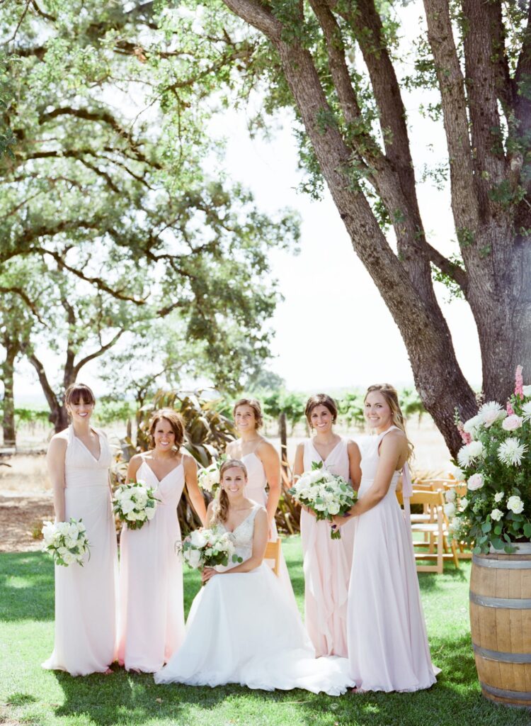 Bridesmaids in pink dresses standing for a portrait before a wedding ceremony. 