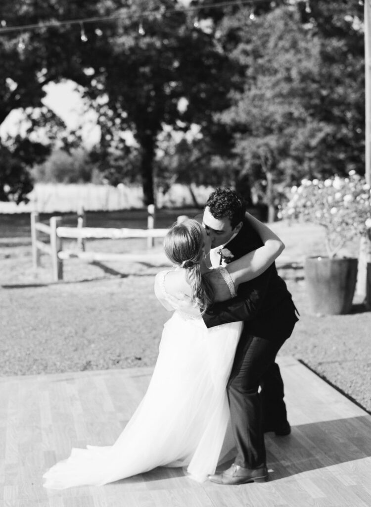 black and white image of a bride and groom dancing at their wedding ending with a kiss.