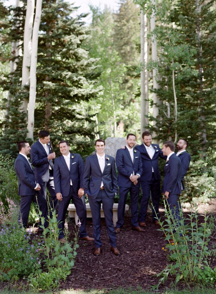 Bridegroom poses outdoor for the camera among the woods with his groomsmen.