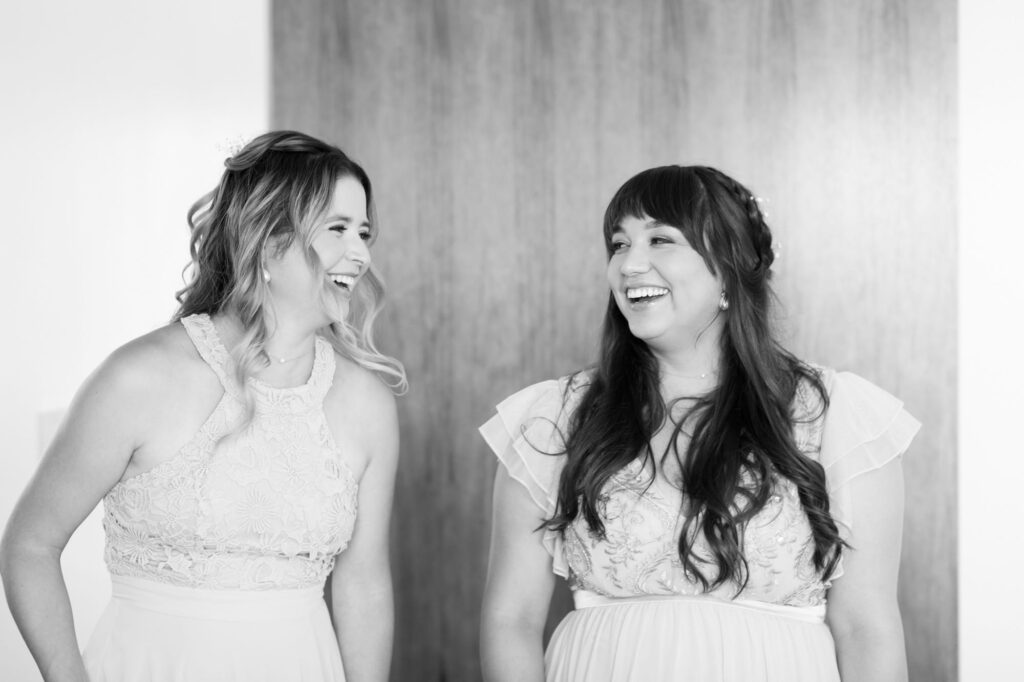 Two bridesmaids smile at each other.