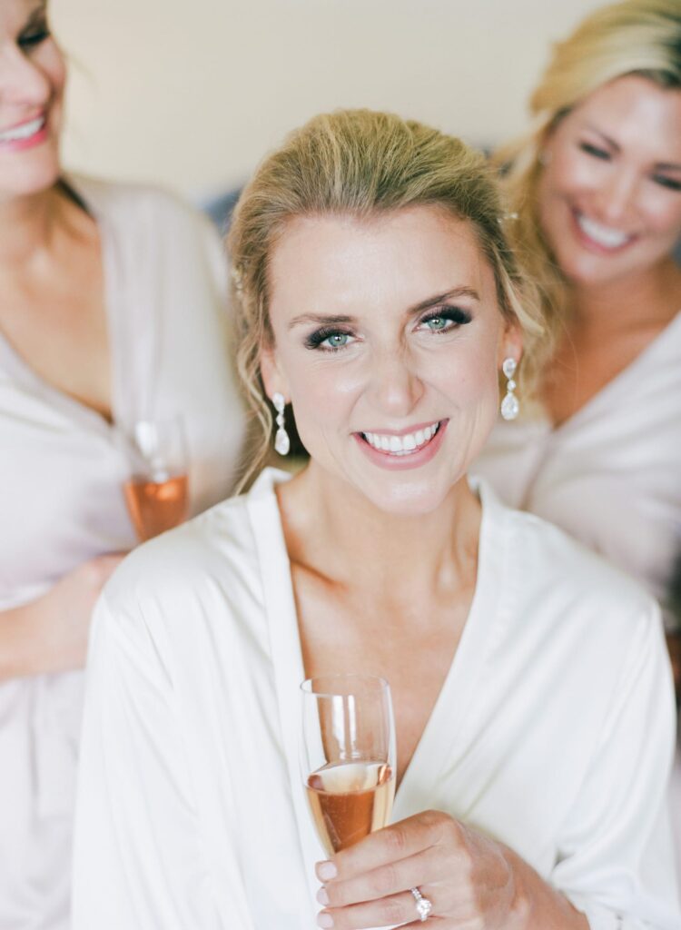 Bride and maids smile with a drink on their hands.