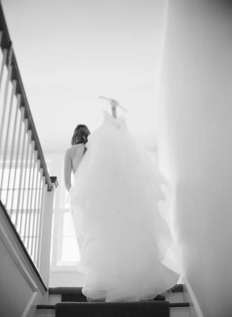 Bride takes her wedding gown up the stairs.