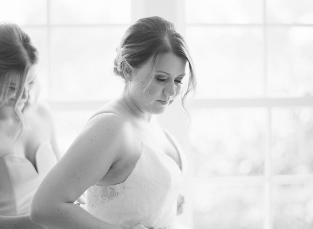 Bridesmaid helps the bride wear her wedding gown.