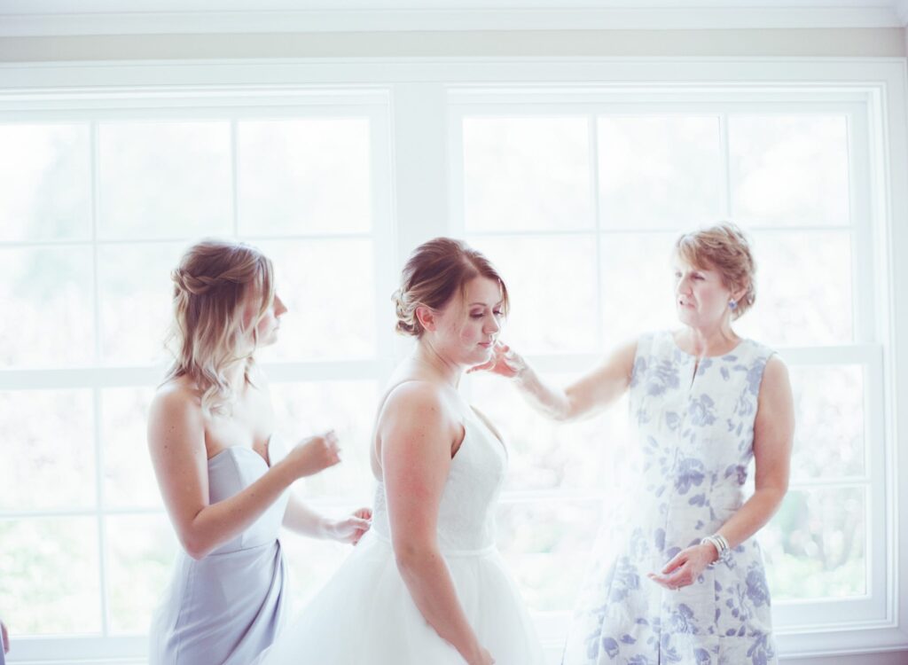 Maids check over the bride in her wedding outfit.