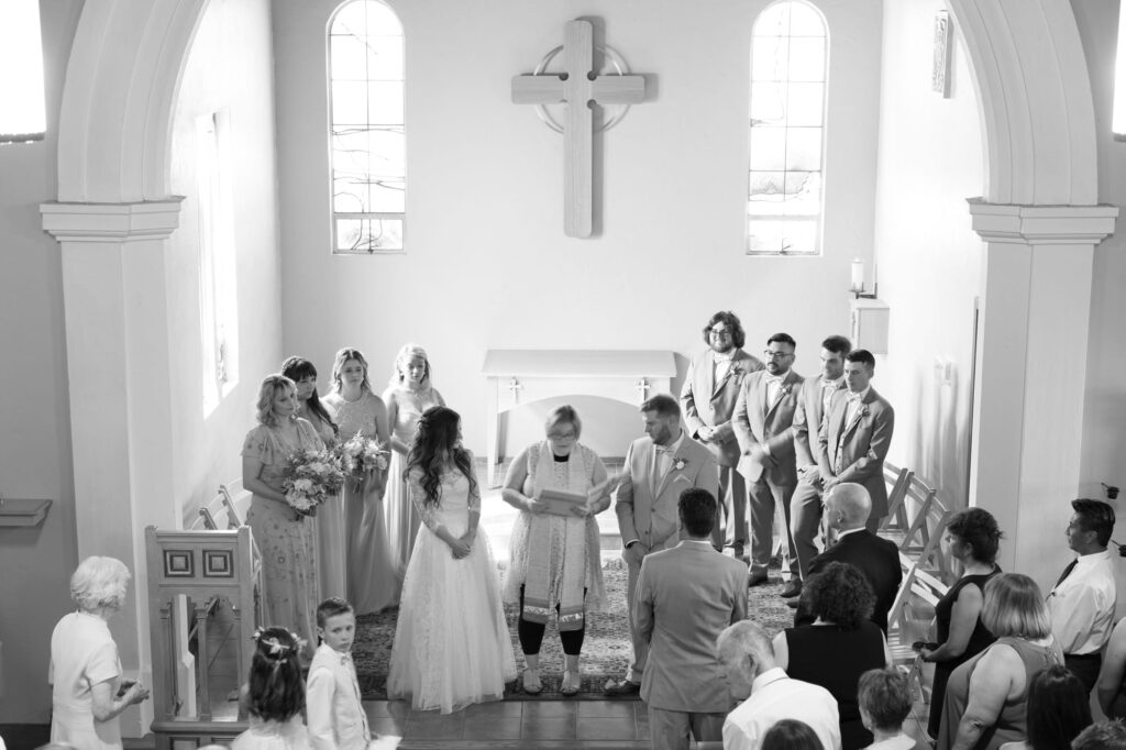 Officiator with bride, groom, and their bridesmaids and groomsmen at a church wedding.