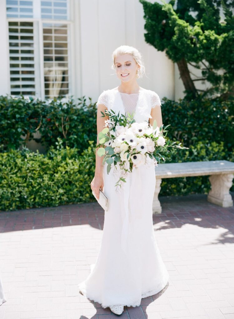 Beautiful bride smiles at the camera with a flower bouquet.