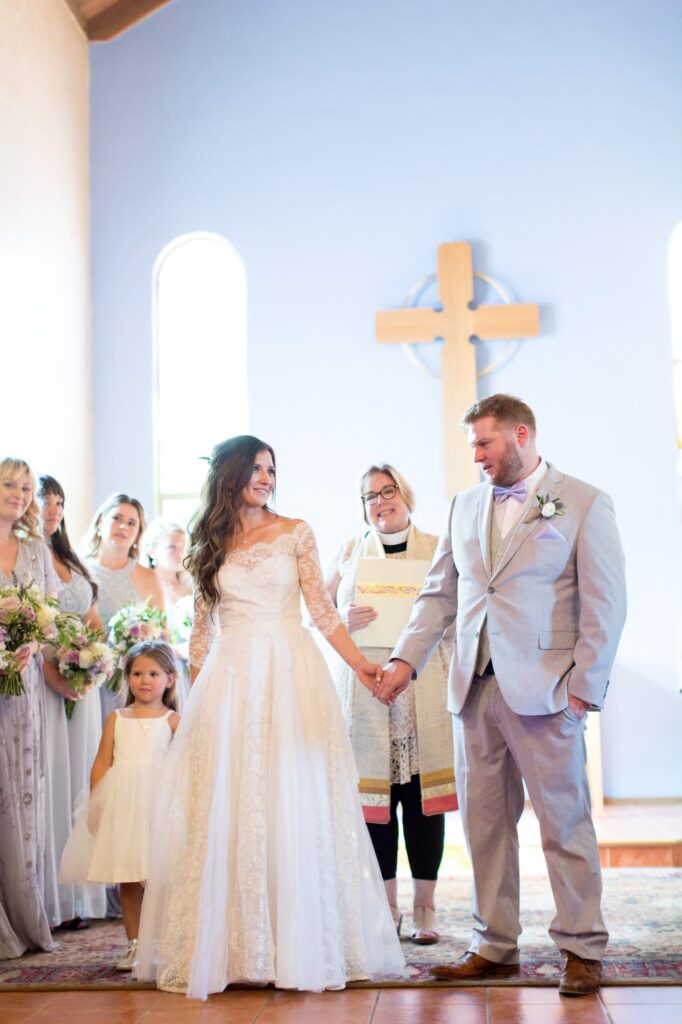 Groom holds his newly pronounced wife's hand at a church wedding.