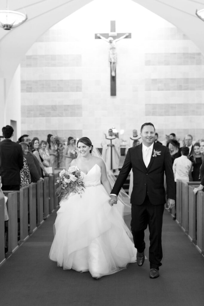 Bride and groom hold hands and walk back up the aisle.