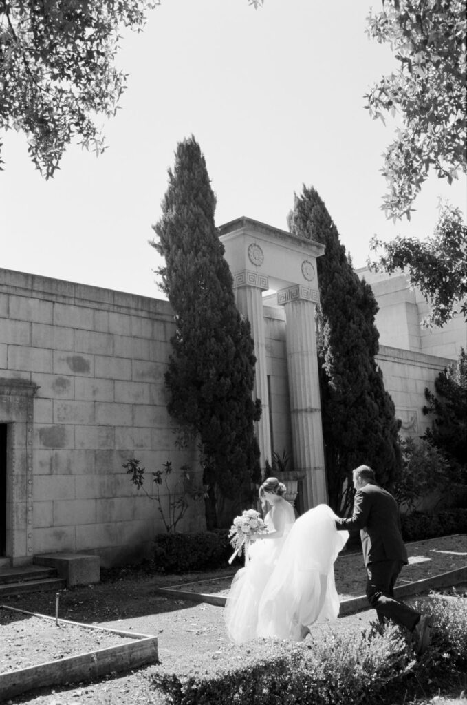 Bride in a gorgeous white wedding gown followed by her husband.