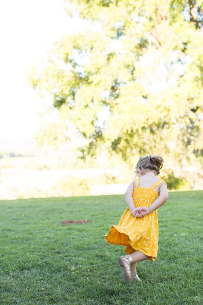 Little girl in yellow dress at a green garden.