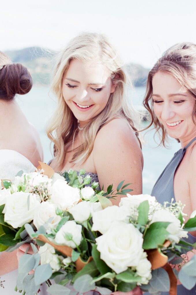 Two smiling bridesmaids hold flower bouquets