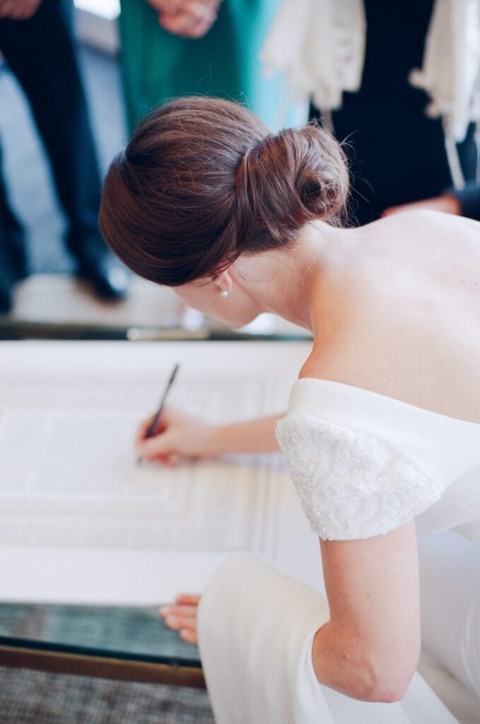 Bride signs on the official marriage documents.