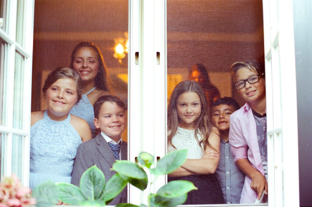 Children at a wedding party peek outside from the window.