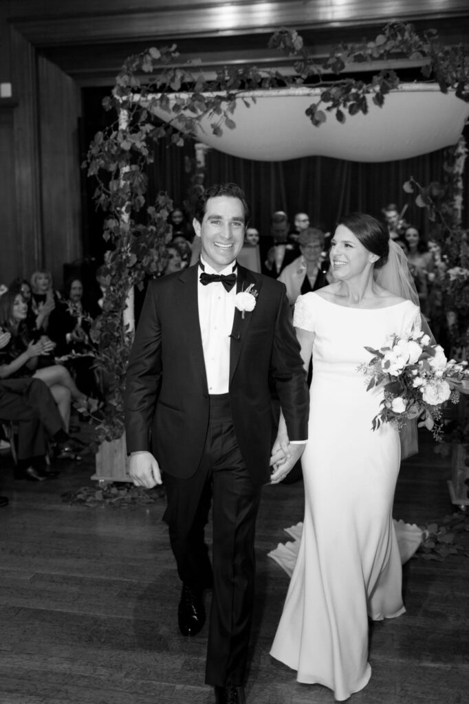 Man holds his wife's hand and leads her to the wedding reception.