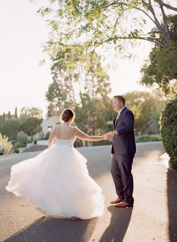 Bride dances in radiant sunset rays with her husband.