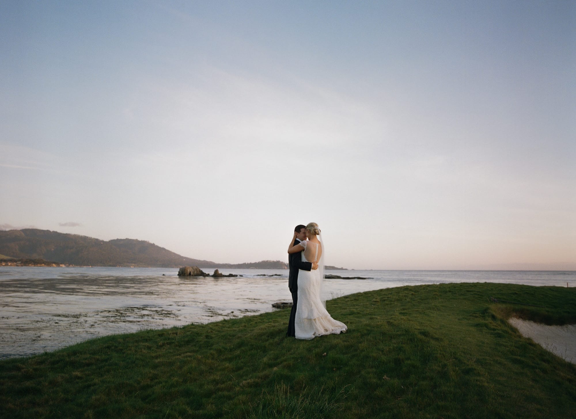 Newly-married couple kiss at Pebble Beach.