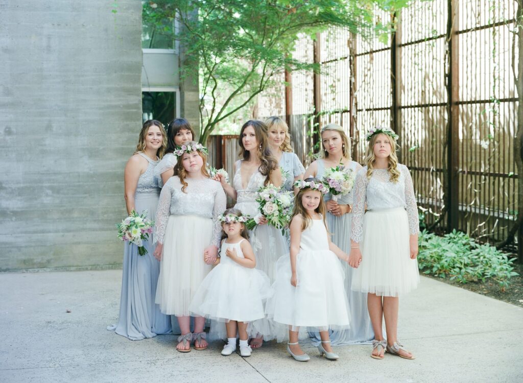 Bride poses with her bridesmaids and little girls in gowns.