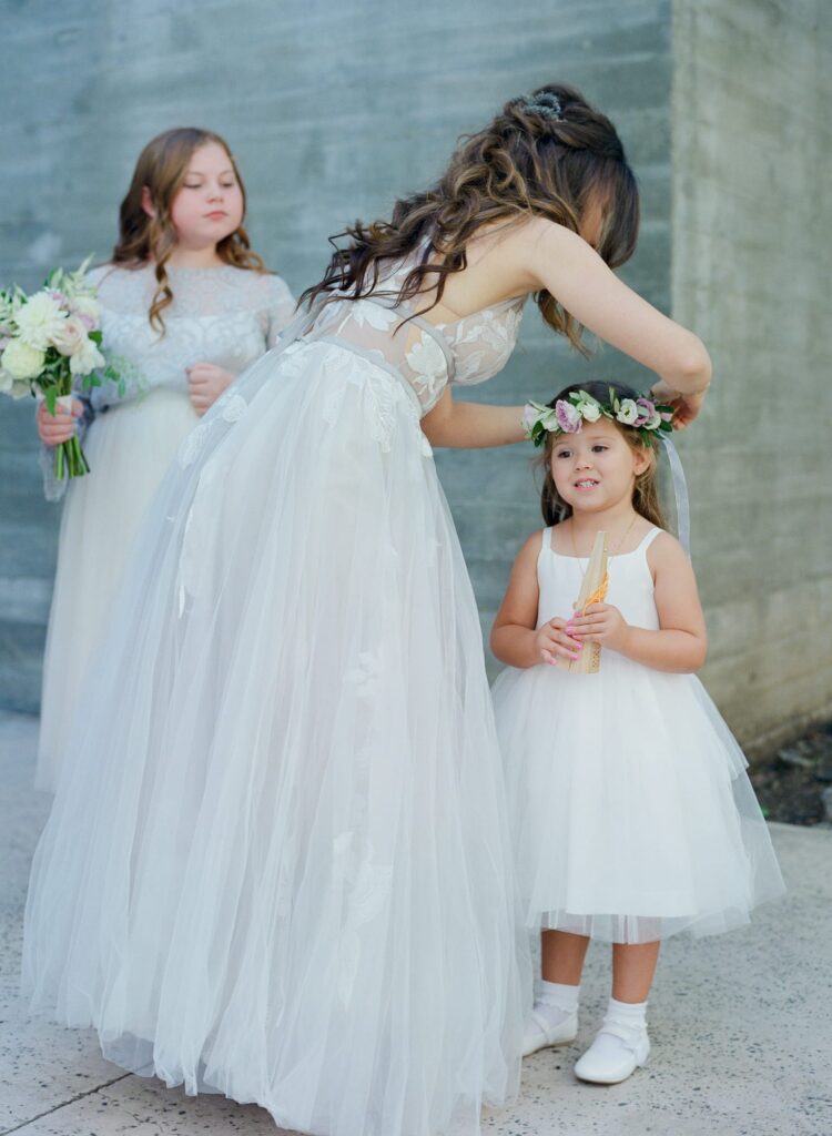 Bride adjusts the wedding crown of a cute little girl.