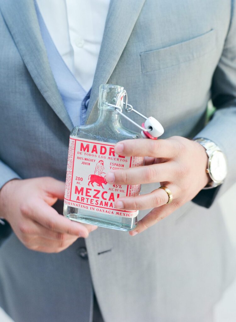 Bridegroom holds a bottle of Madre Mezcal Artesanal.