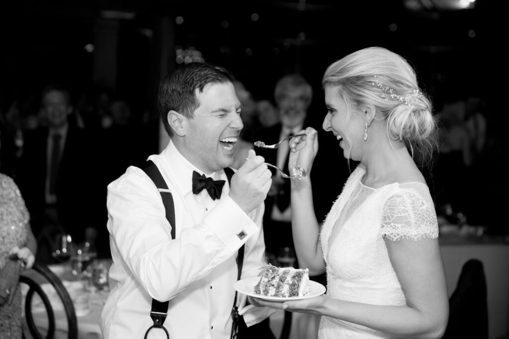 Newlyweds feed each other cakes at their afterparty.