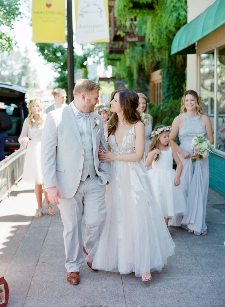 Elated bride and groom walk in front of their bridesmaids.