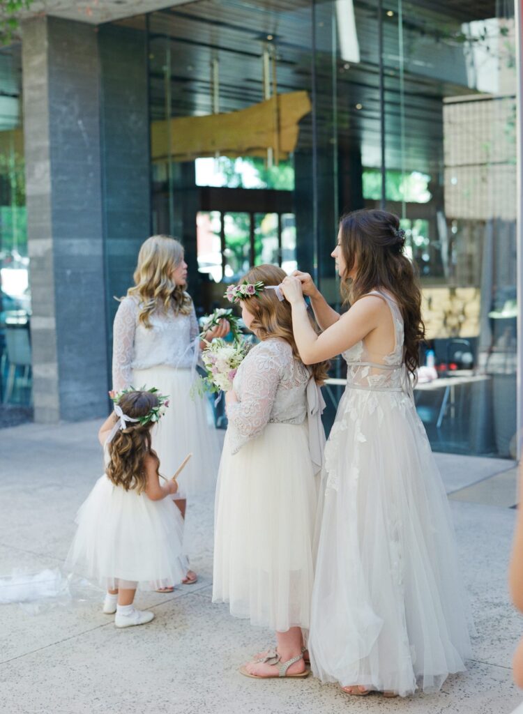 Bride helps little girls at her wedding with their attires.