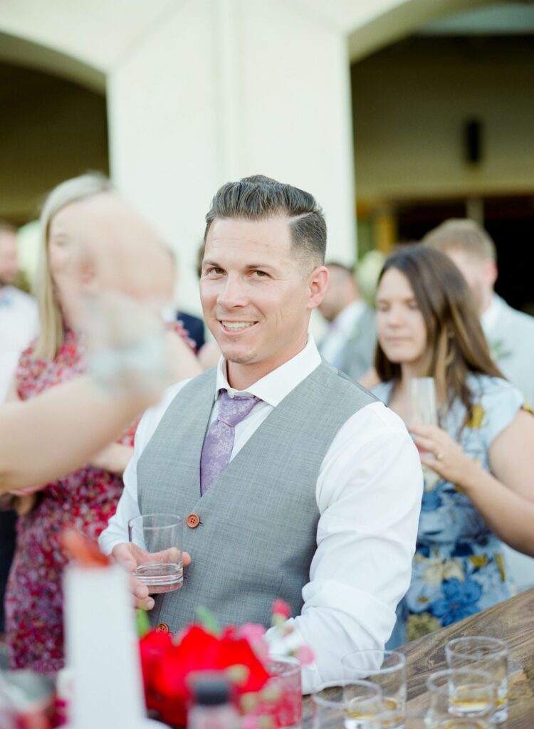 Man grabs a drink at a wedding reception party with other guests.