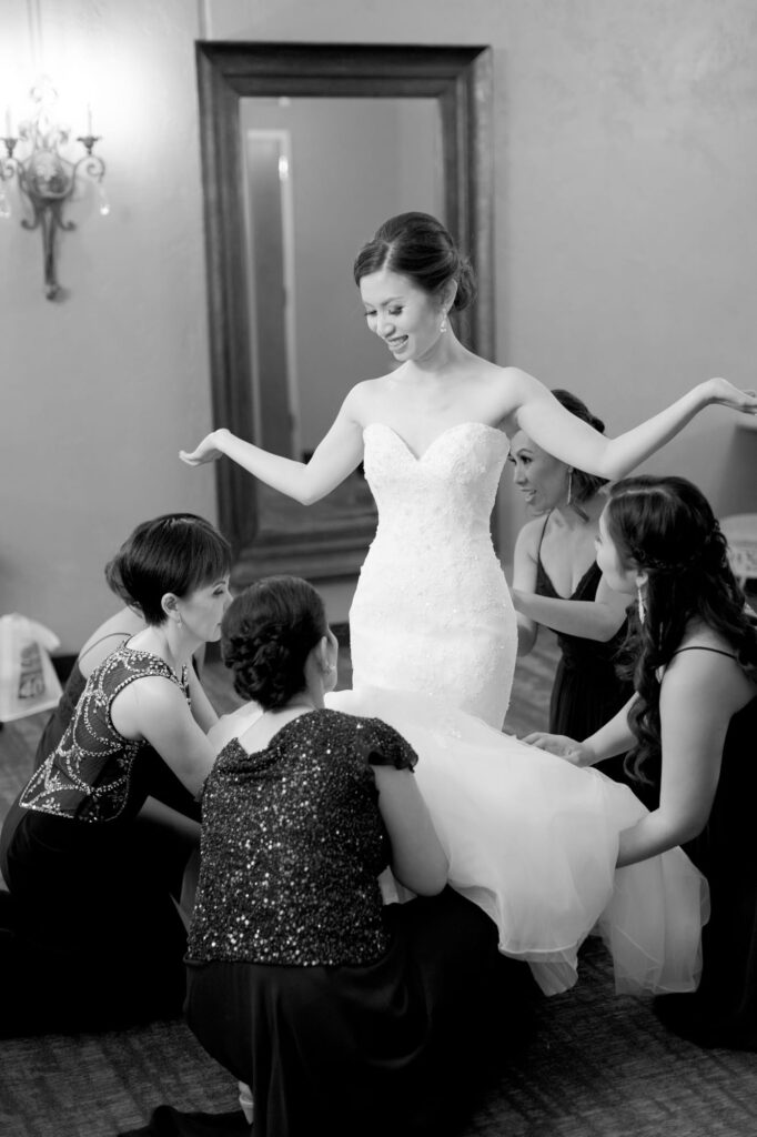 Bridesmaids help with the bride's white wedding gown.