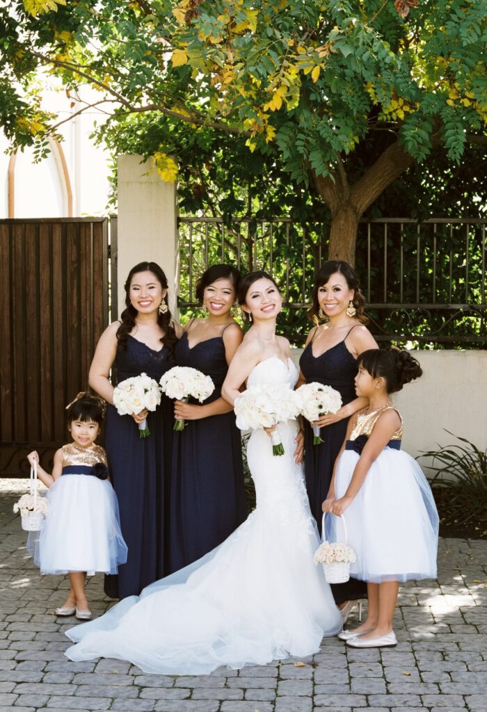 Bride poses outdoors with her bridesmaids.