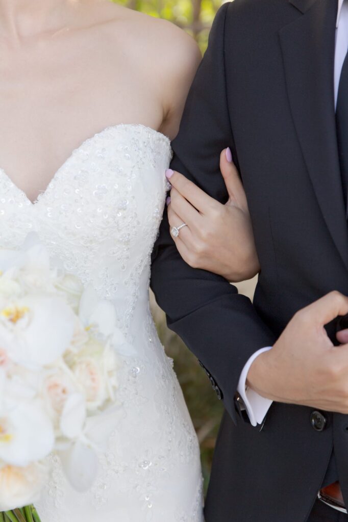 Classy bride holds her groom by his arm.