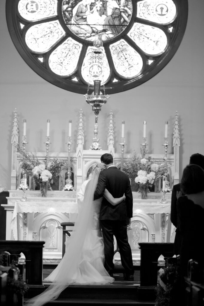 Newly pronounced husband and wife hug each other in front of the officiant.