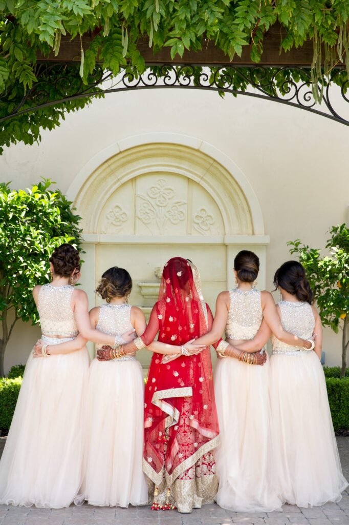 Indian-style wedding dress and veil for the bride, and bridesmaids wear creamy-white gowns.